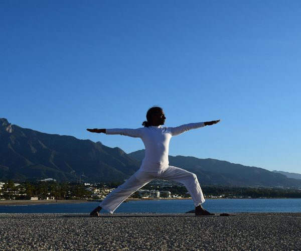 Silhouette of a person in a powerful warrior yoga pose against a sunrise.